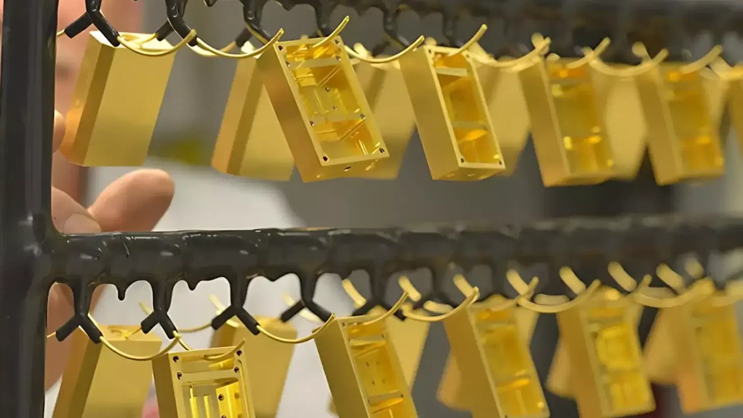 Gold-plated metal components hanging on a rack after the electroplating process