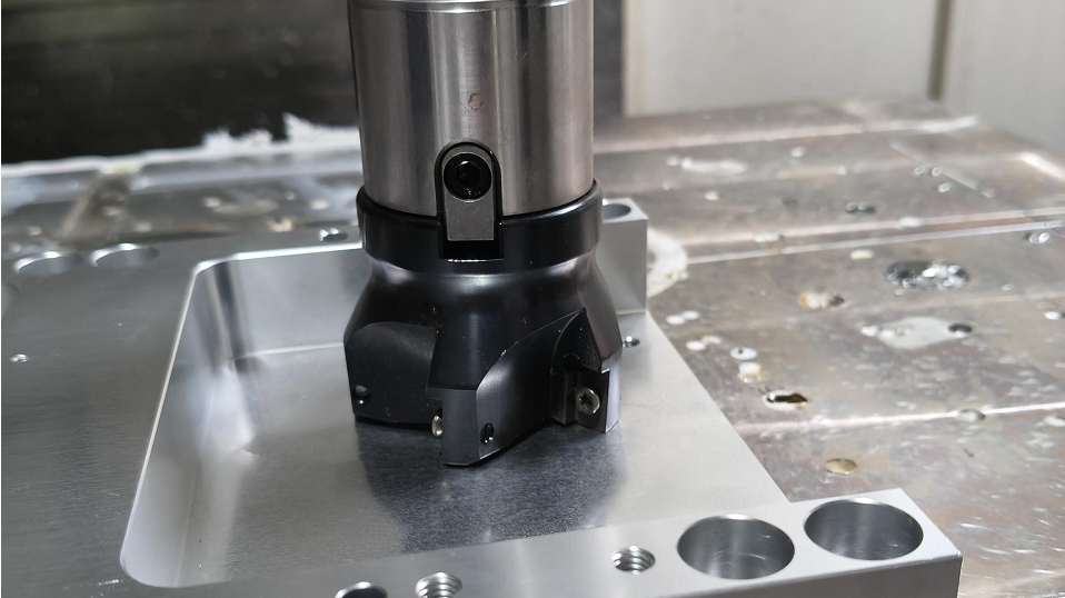 Face mill cutter with carbide inserts sweeping across a metal workpiece to cut a flat surface